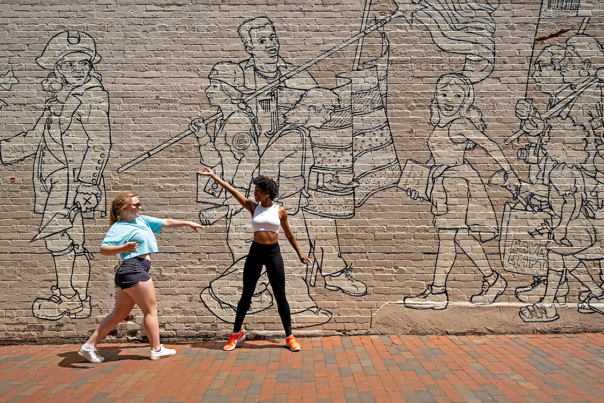 students dance in front of mural