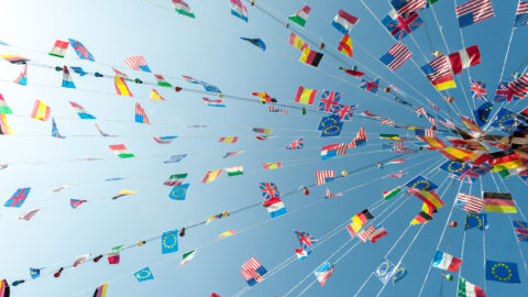 flags of many nations blowing against the sky in a clear summer afternoon