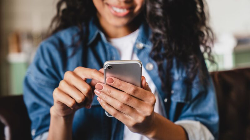 woman smiling while using smart phone to contact UNC CAPS