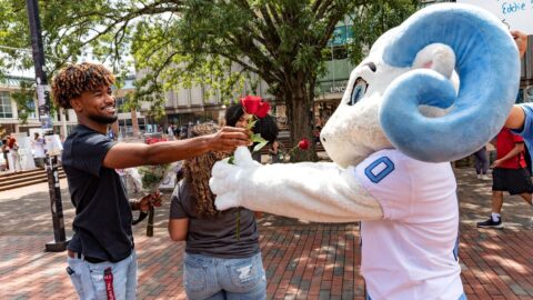 Student and RJ exchange a rose in the pit, an example of showing care and being the best kind of friend at Carolina