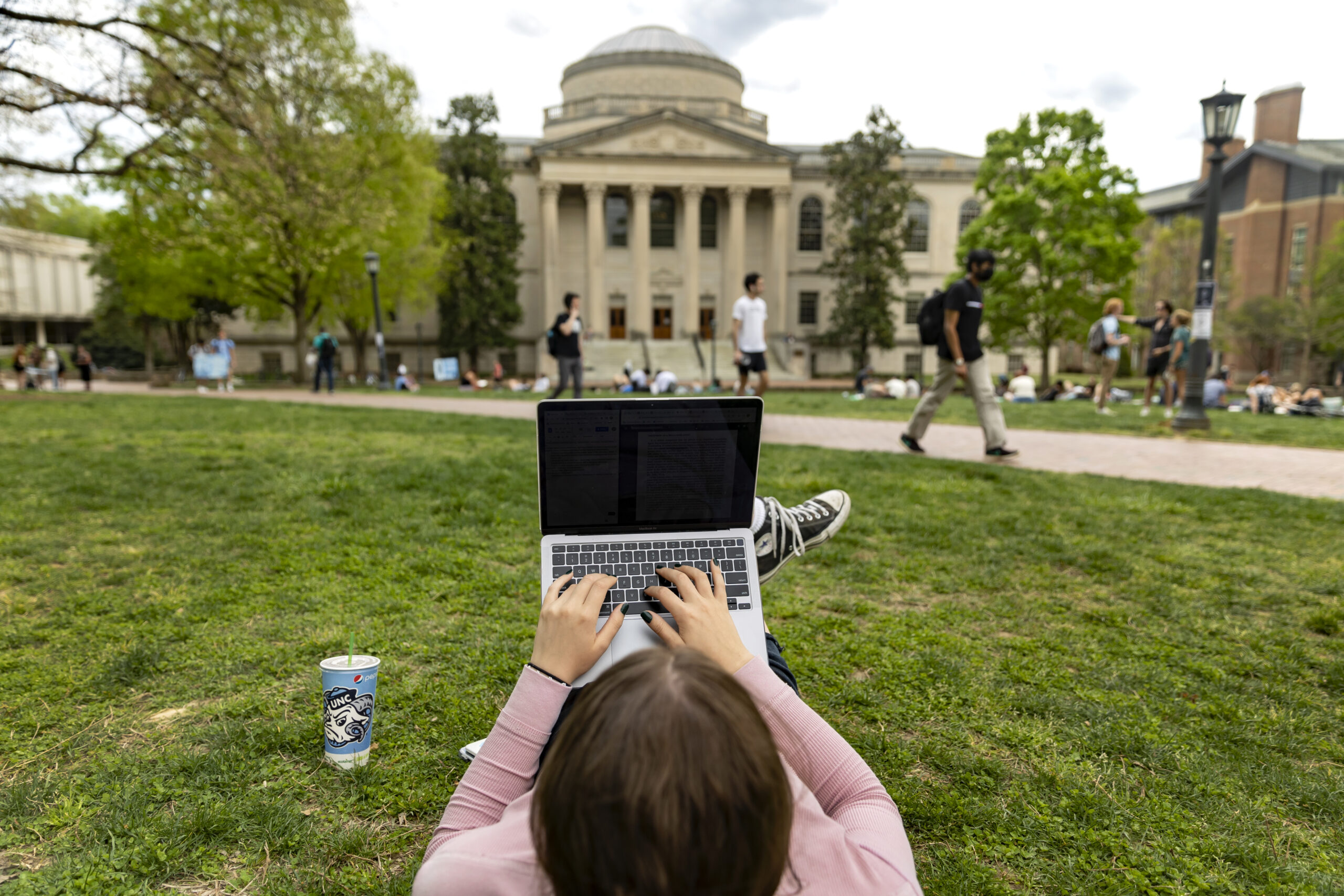 Student using their computer on the quad facing Wilson Library.
